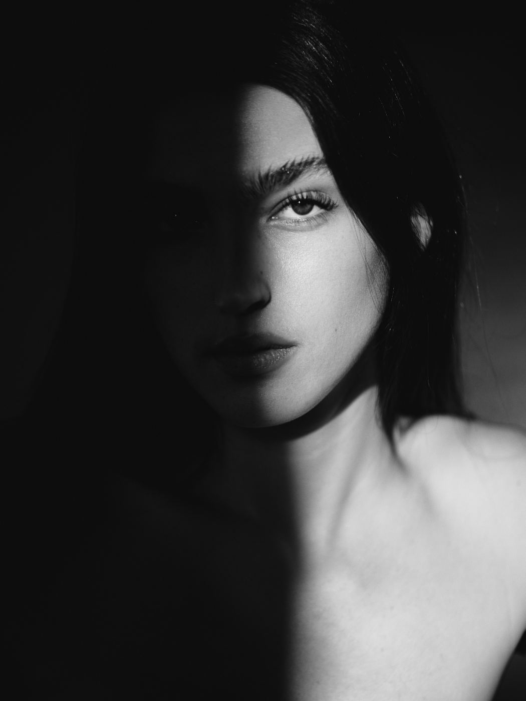 Low-key black and white close-up portrait of a woman in shadow, by Armand Sanchez